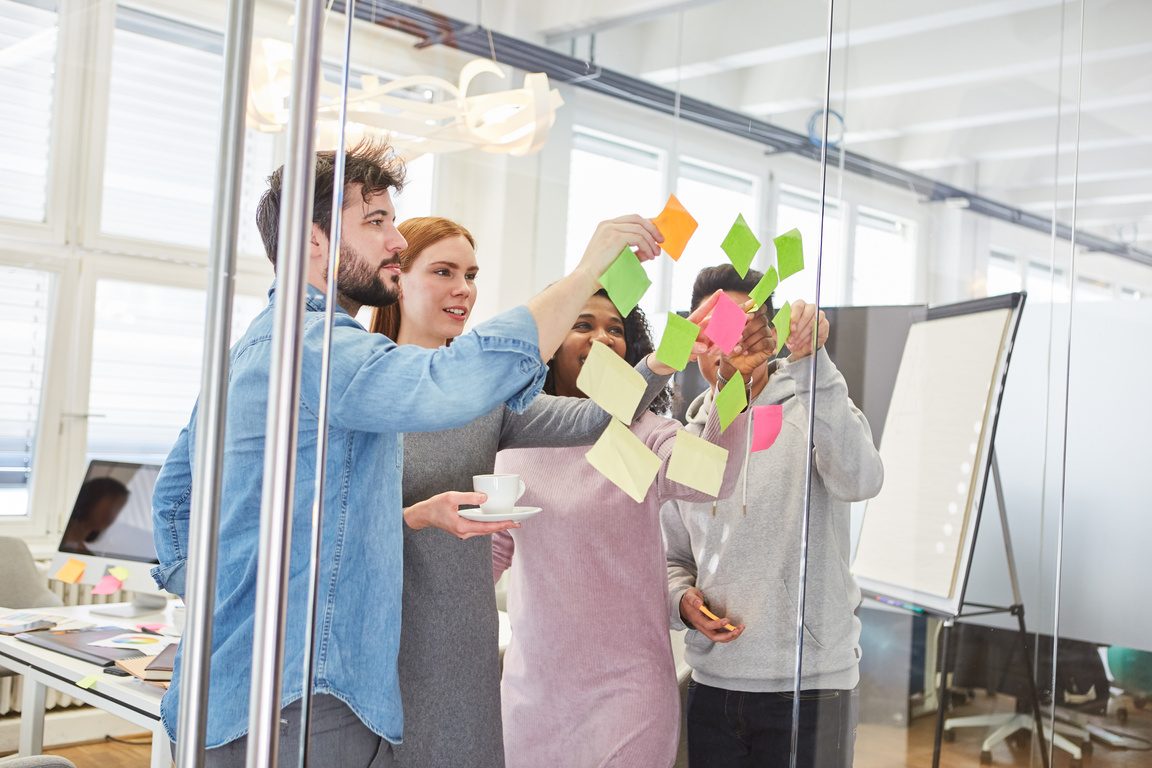 Workshop-Gruppe sammelt Ideen auf Haftnotizen an einer Glaswand